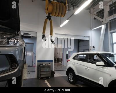 Auto mit offener Motorhaube am Lift und weißem SUV im Autoservice. Podolsk, Region Moskau - April 2019 Stockfoto