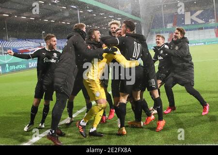 13. Januar 2021, Schleswig-Holstein, Kiel: Fußball: DFB-Pokal, Holstein Kiel - Bayern München, 2. Runde, im Holstein-Stadion. Kieler Spieler feiern ihren Sieg mit Torwart Ioannis Gelios (M) nach dem Elfmeterschießen. (Wichtiger Hinweis: Der DFB verbietet die Verwendung von Sequenzbildern im Internet und in Online-Medien während des Spiels (einschließlich Halbzeit). Sperrfrist! Das DFB erlaubt die Veröffentlichung und Weiterverwendung der Bilder auf mobilen Geräten (insbesondere MMS) und über DVB-H und DMB erst nach Ende des Spiels). Foto: Christian Charisius/dpa - WICHTIGER HINWEIS: Gemäß wi Stockfoto