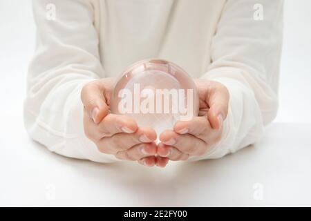 Nahaufnahme der Hände, die einen Glaskugel halten Stockfoto