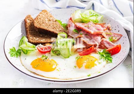 Englisches Frühstück - Spiegelei, Speck, Tomaten und Brot. Stockfoto
