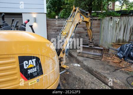 Mini Bagger graben einen Graben mechanisch zu reparieren eine gebrochene Drainageschlauch, Sydney, Australien Stockfoto