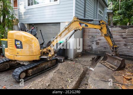 Mini Bagger graben einen Graben mechanisch zu reparieren eine gebrochene Drainageschlauch, Sydney, Australien Stockfoto