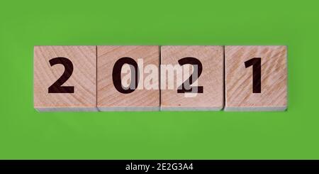 2021 Neujahr auf Holzwürfeln auf grünem Hintergrund. Geschäftsjahresstart-Konzept. Stockfoto