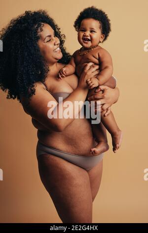 Afrikanische Mutter und Baby stehen zusammen am Muttertag. Lächelnde Mutter und Kind zum Ausdruck bringen Glück und Liebe. Stockfoto