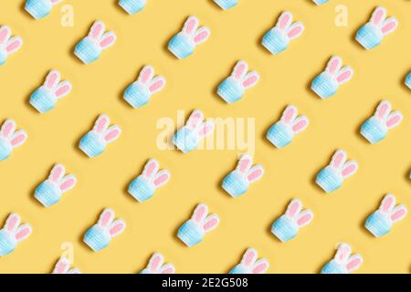 Ostern und Quarantäne. Nahtloses Muster eines Kaninchens in einer schützenden medizinischen Maske auf gelbem Hintergrund. Stockfoto