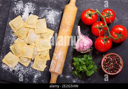 Frische Ravioli mit Gemüse auf dunklem Brett, Draufsicht Stockfoto