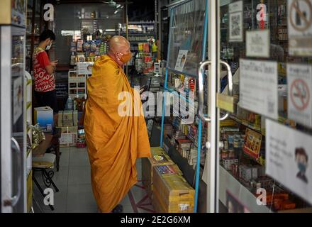 Mönchshoppen in einer Apotheke mit COVID-Gesichtsmaske wie vorgeschrieben in Thailand Südostasien Stockfoto