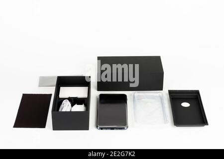 Auspacken von Touchscreen-Smartphone, Papier-Box, Silikon-Abdeckung, Kopfhörer und sauberes Tuch. Studio-Aufnahmen auf weißem Hintergrund. Stockfoto