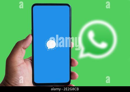 Kathmandu, Nepal - Januar 14 2021: Man hält Smartphone mit Signal App Logo gegen WhatsApp Logo im Hintergrund. Stockfoto