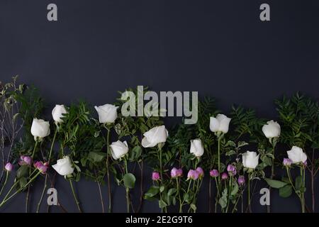 Draufsicht auf viele weiße und rosa Rosen mit Grün Blätter auf schwarzem Hintergrund platziert Stockfoto