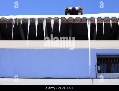 Eiszapfen auf der hübschen Kante eines Daches Stockfoto