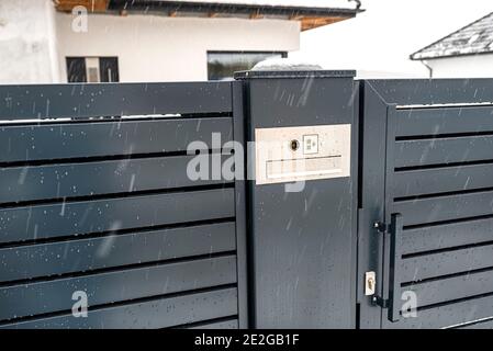 Ein modernes Videotelefon mit Briefkasten und kabellosem Kartenleser, in anthrazitfarbenem Panelzaun montiert, sichtbares Wicket, es regnet im Winter, in Th Stockfoto