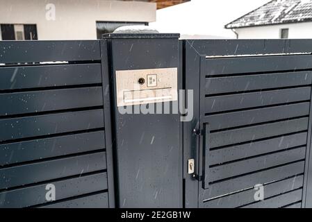 Ein modernes Videotelefon mit Briefkasten und kabellosem Kartenleser, in anthrazitfarbenem Panelzaun montiert, sichtbares Wicket, es regnet im Winter, in Th Stockfoto