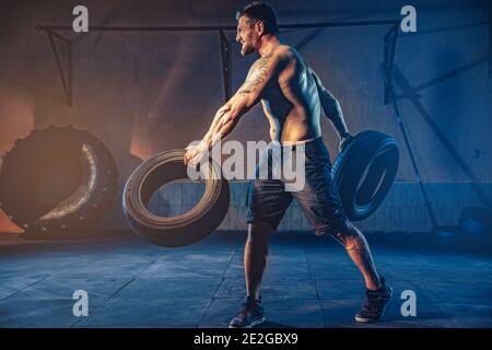 Bodybuilding-Training, bärtige starke Sportler mit muskulösen Körper heben schwere Rad in der Turnhalle. Stockfoto