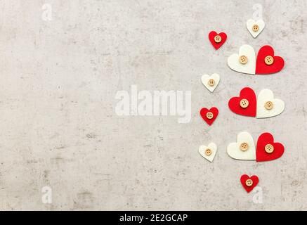 Valentinstag minimalistisches Konzept. Dekorative rote Herzen auf betontem Hintergrund. Stockfoto