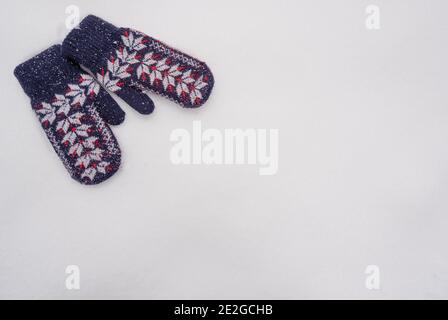 Weihnachten Neujahr Winter Hintergrund mit warmen Fäustlingen im Schnee. Winterhandschuhe auf weißem Schneehintergrund mit leerem Platz für Ihren Text. Stockfoto