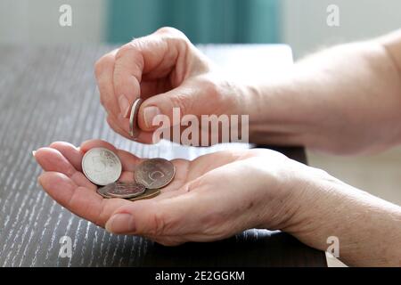 Ältere Frau zählt russische Rubel in Münzen, weibliche Hände aus der Nähe. Konzept der Armut in Russland, Rentenzahlungen, Rentner mit Metallgeld Stockfoto