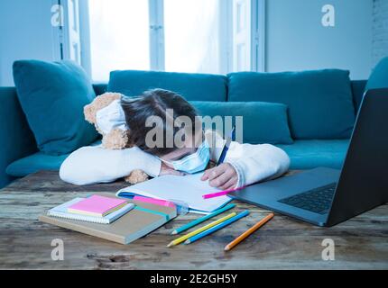 E-Learning. Gelangweilte und depressive Mädchen mit Teddybär und Gesichtsmaske auf Laptop Lernen zu Hause in Online-Klassen als Schule bleiben geschlossen wegen New COV Stockfoto