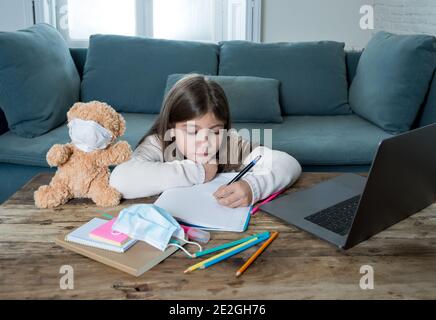 E-Learning. Gelangweilte und depressive Mädchen mit Teddybär und Gesichtsmaske auf Laptop Lernen zu Hause in Online-Klassen als Schule bleiben geschlossen wegen New COV Stockfoto