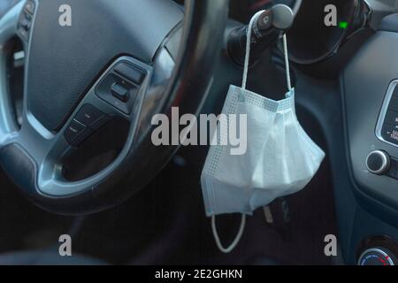 Schutzmaske, die am Lenkrad des Autos hängt Stockfoto