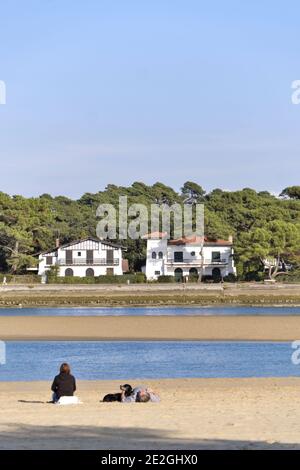 Hossegor (Südwestfrankreich): Senioren von hinten am Strand mit Blick auf die Villen am See. Ferienhaus mit geschlossenen Fensterläden auf der Stockfoto