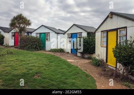 Bunte Türen auf Ferienchalets verlassen wegen der Klippenerosion in Brightstone Bay, Isle of Wight Stockfoto