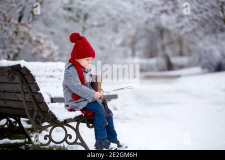 Schöne Kleinkind Kind, niedlichen Jungen, spielen in verschneiten Park Winterzeit, bewölkten Tag Stockfoto