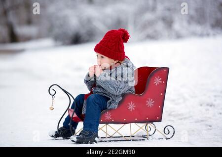 Schöne Kleinkind Kind, niedlichen Jungen, spielen in verschneiten Park Winterzeit, bewölkten Tag Stockfoto