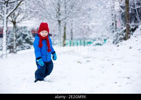 Schöne Kleinkind Kind, niedlichen Jungen, spielen in verschneiten Park Winterzeit, bewölkten Tag Stockfoto