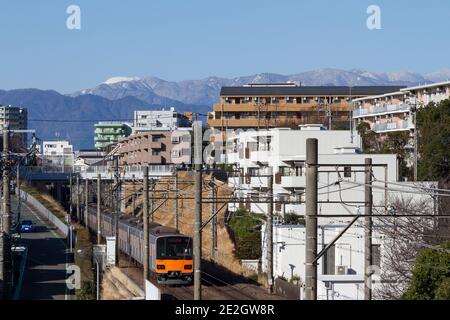 Der Berg Fuji über dem Vorort Kanagawa mit einem Nahverkehrszug der Serie Tobu 50050, der durch Tsukumino, Japan, fährt, Stockfoto