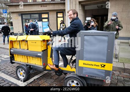 Hamburg, Deutschland. Januar 2021. Anjes Tjarks (Bündnis 90/die Grünen), Senatorin für Verkehr und Mobilitätswandel in Hamburg, testet bei einer Fotogelegenheit ein elektrisches Lastenrad der Deutschen Post, um gemeinsam ein Mikrodepot für Güterlogistik in der Innenstadt zu präsentieren. Das gemeinsame Projekt von Hamburger Hochbahn, Rewe, Hermes, UPS und Deutsche Post soll die Güterlogistik im Stadtverkehr mit dem Lastenrad testen. Quelle: Christian Charisius/dpa/Alamy Live News Stockfoto