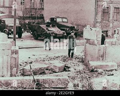 Bau der Berliner Mauer. Spalt in der Wand. Kommunistische Grenzposten inspizieren eine Lücke in der Berliner Mauer, wo zwei ostdeutsche Bauarbeiter Stockfoto