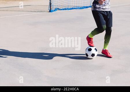 Nicht erkennbarer Fußballspieler tritt auf den Ball in einem Beton Fußballplatz, Konzept der gesunden Lebensweise und städtischen Sport in der Stadt, kopieren Raum Stockfoto