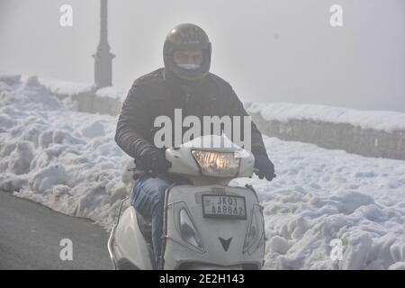 Srinagar, Kaschmir. Januar 2021. Ein Motorradfahrer fährt während eines Nebels in Srinagar auf einer Straße. Die kalte Welle intensivierte sich in Kaschmir mit einem Rückgang der Mindesttemperaturen in den meisten Teilen des Tals am Donnerstag. Srinagar verzeichnete eine Mindesttemperatur von minus 8.4 Grad Celsius, die niedrigste Temperatur, die nach 29 Jahren in der Stadt aufgezeichnet wurde. Kredit: SOPA Images Limited/Alamy Live Nachrichten Stockfoto