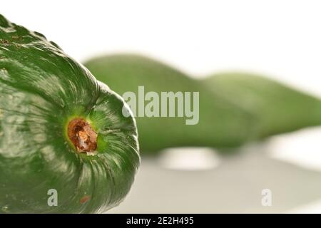 Auf der linken Seite, Makro, Teil einer reifen grünen appetitlich Avocado, im Hintergrund - zwei ganze Früchte, auf weißem Hintergrund. Stockfoto