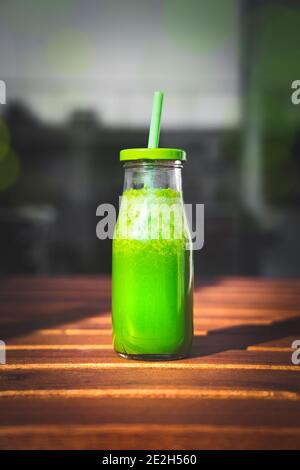 Eine Flasche frischen gesunden grünen Detox Smoothie mit Spinat, grünem Apfel, Kiwi und Grünkohl auf dem Holztisch Stockfoto