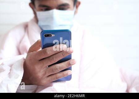 Kranker Mann in chirurgische Gesichtsmaske mit Smartphone, selektive Fokus Stockfoto