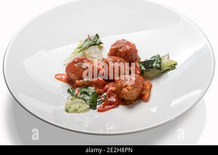 Polpette al Sugo, italienische Fleischbällchen mit Tomatensauce mit Gemüse in weißem Teller isoliert auf weiß Stockfoto