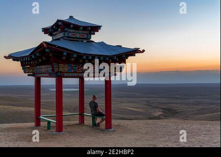 Der kahle Mensch betrachtet die Welt in einer Pagode zur Meditation Oder Pavillon im buddhistischen Stil in Steppe mit wolkenlosem Himmel Stockfoto