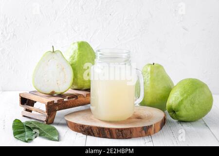 Köstliche schöne Guava Obst mit frischem Saft auf hellen weißen Holztisch Hintergrund isoliert gesetzt, Nahaufnahme. Stockfoto