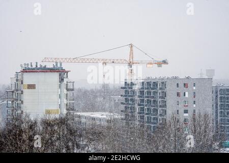 Industrielandschaft mit unfertigen Hochhaus und Kran im Winter während Schneefall, Riga, Lettland Stockfoto