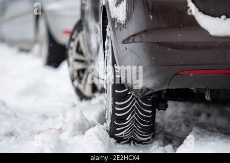 Rückansicht des Autos mit Winterreifen auf verschneiten Straßen, Nahaufnahme Stockfoto