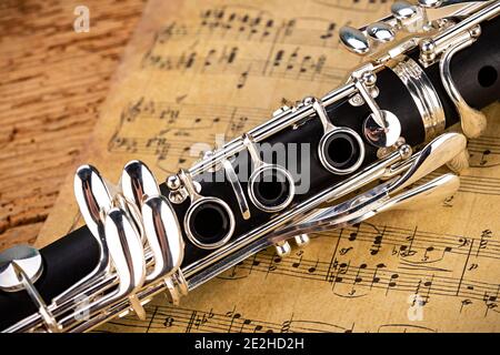 Schwarze Holzklarinette silbernes Holzblasinstrument mit altem Vintage-Notenblatt auf Retro-Eichenholz-Hintergrund. Klassisches Orchestersym Stockfoto