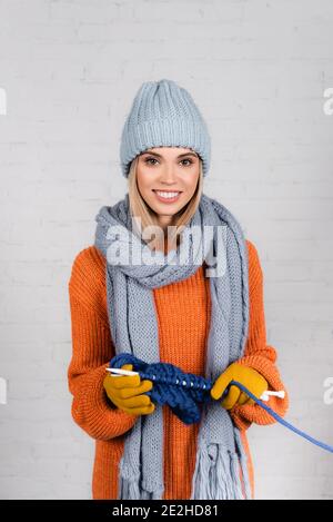 Lächelnde Frau in warmen Kleidern stricken auf weißem Hintergrund Stockfoto