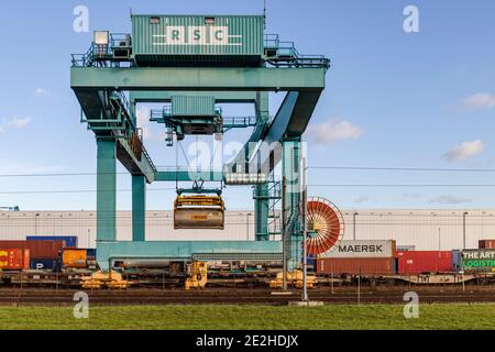 Rotterdam, Niederlande - 2021-01-13: Kranladen von Containern auf einem Zug am RSC Rail Terminal in Rotterdam von der Seite aus gesehen Stockfoto