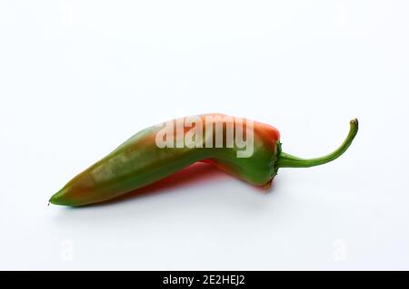 Eine Schote von heißem roten unreifen Pfeffer. Auf weißem Hintergrund. Stockfoto