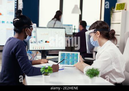Finanzteam des großen Unternehmens dabei finanzielle Analyse trägt Gesichtsmaske während covid19. Verschiedene Gruppe von Geschäftsleuten arbeiten und kommunizieren zusammen im Büro mit neuen normalen, unter Beachtung der sozialen Distanz. Stockfoto