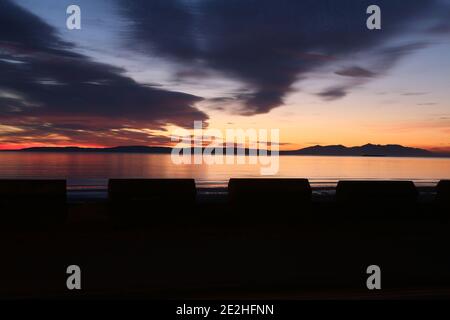 Isle of Arran, Schottland, Großbritannien. Sonnenuntergang über der Insel vom Strand in Ayr. Bekannt als der schlafende Riese aufgrund seiner Umrisse, besonders von der Ayrshire Coast aus gesehen. Stockfoto