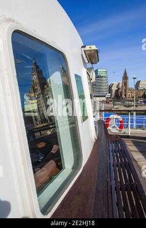 Eine Mersey-Fähre im Bild, die am Liverpool Pier Head mit der Pfarrkirche St. Nicholas und dem Royal Liver Gebäude im Hintergrund anlegt. Stockfoto