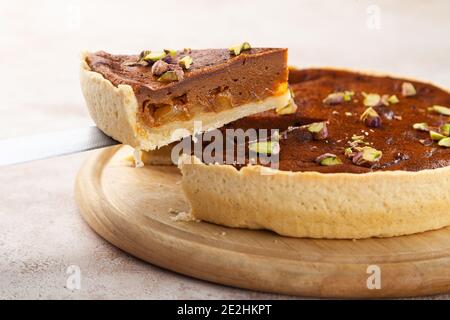 Hausgemachter Kuchen mit Schokolade, Karamell, Pistazie, geschnittenes Stück Kuchen auf Messer, Holzplatte, Kopierraum, Platz für Text, Seitenansicht, Nahaufnahme Stockfoto